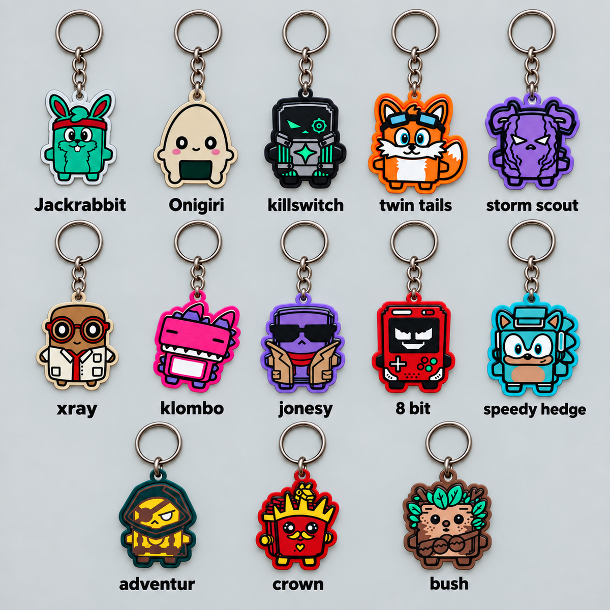 Grid of flat 2D character keychains on silver key rings, including a green rabbit, a rice ball, a dark robot, a fox with goggles, a purple hooded character, a scientist, a pink creature, a character in sunglasses, a red handheld console, a blue hedgehog, a masked adventurer, a crown fry box and a leafy bush, each with a name label | sgc-photo-ok
